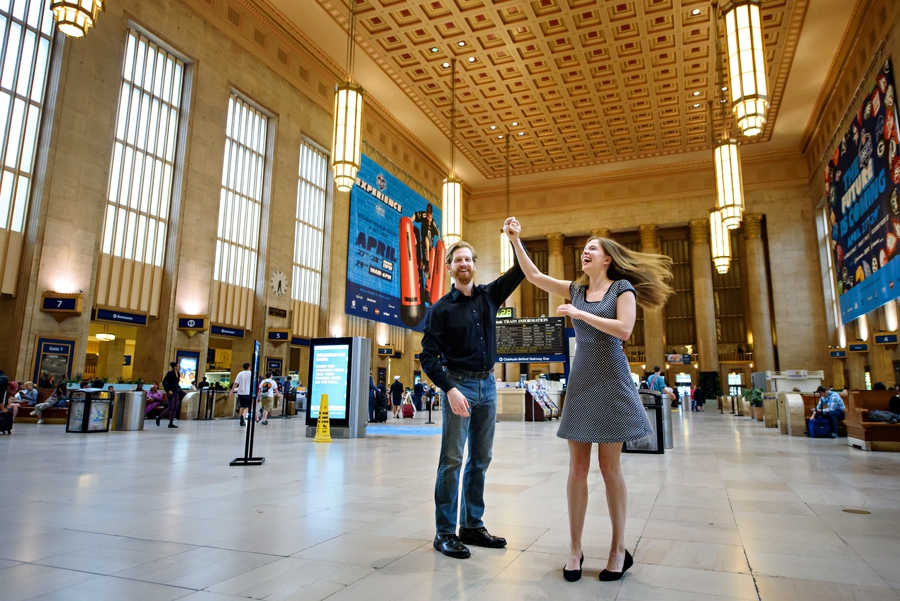 A man dances with his fiance in 30th street station in philadelphia for their engagement session.